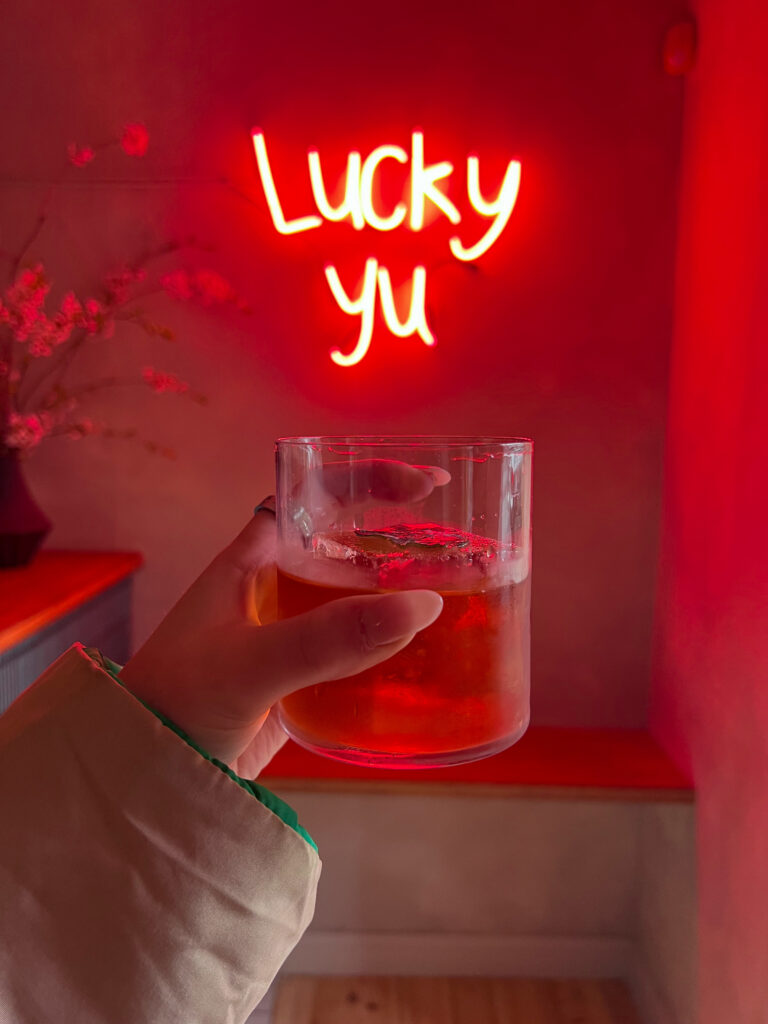 Cocktail in front of neon sign at Lucky Yu
