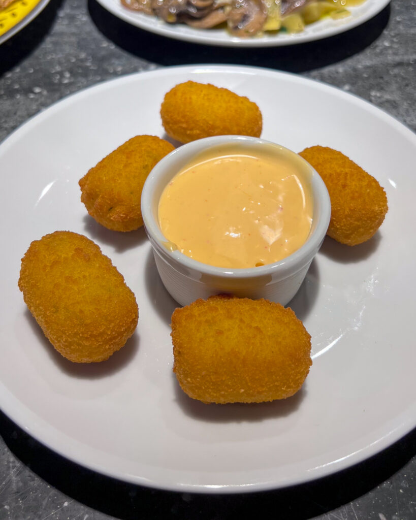 Five croquettes surrounding a jar of spicy mayo