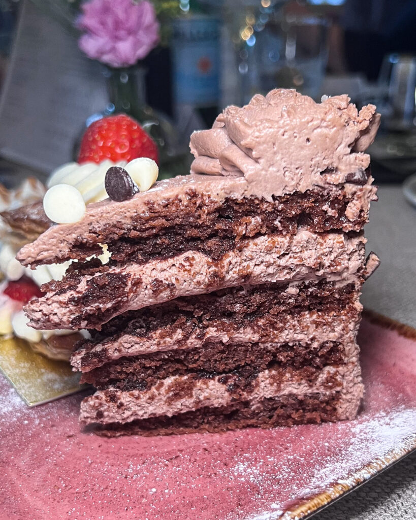 Tall slice of chocolate cake with chocolate icing from Le Bistrot