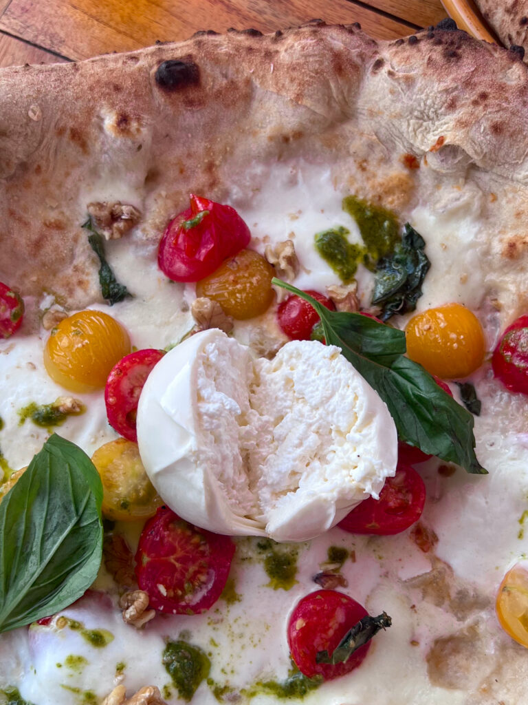Oozing burrata on top of pizza at Napole Pizzeria