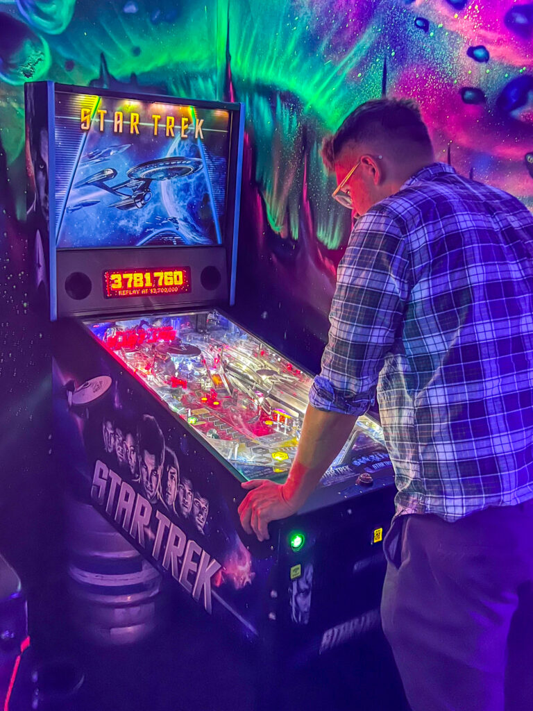 Person playing retro pinball machine at NQ64