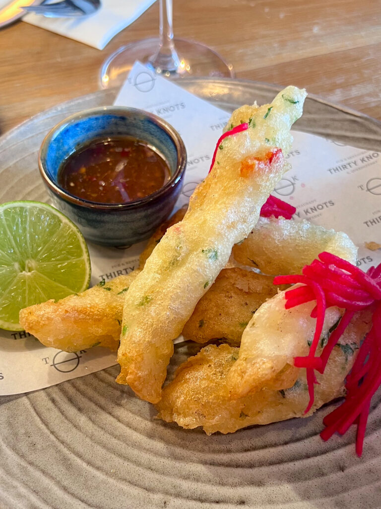 Fried calamari with lime wedge and sweet chilli dip and pink garnish