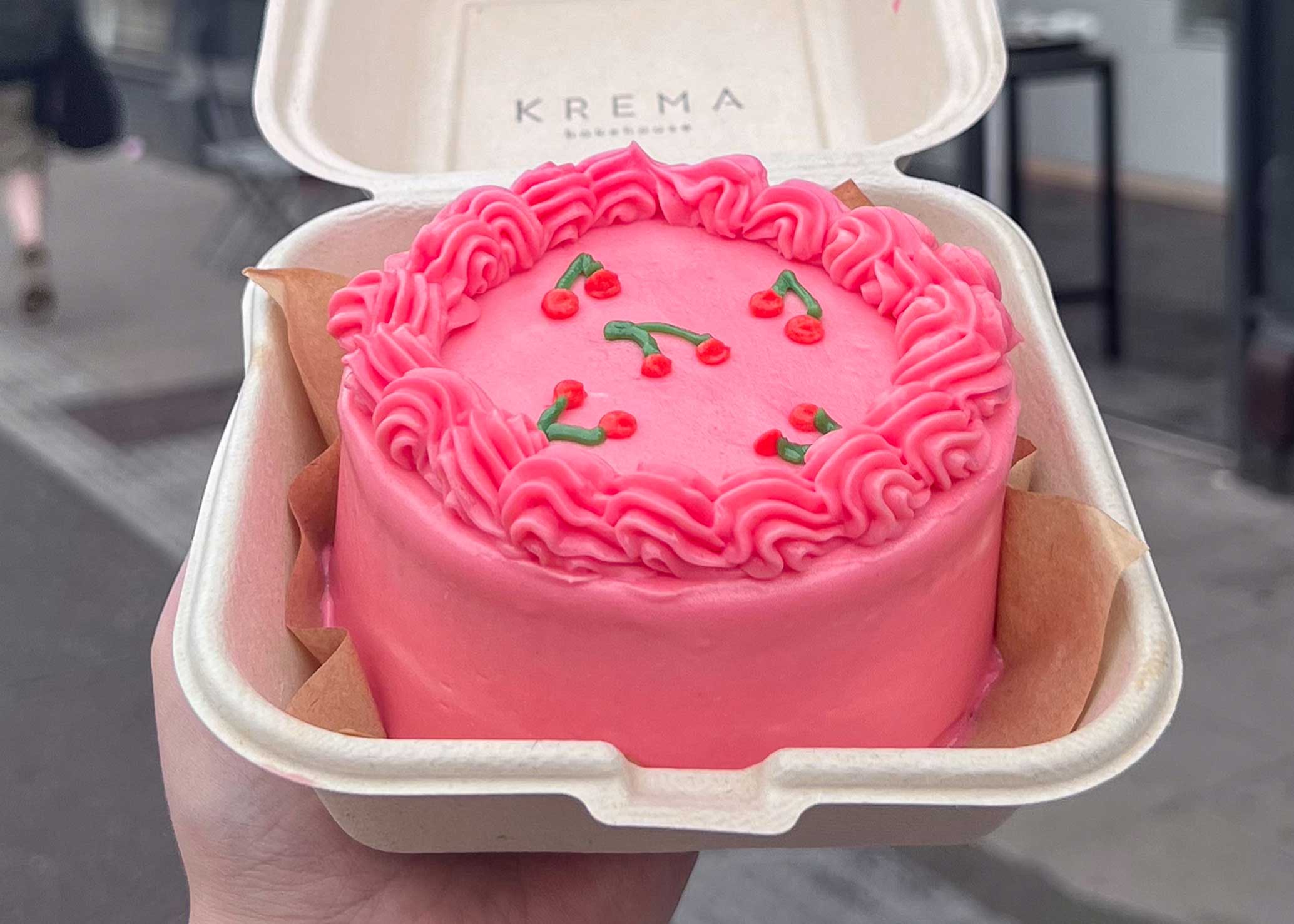 Small pink bento cake in a krema branded takeaway box