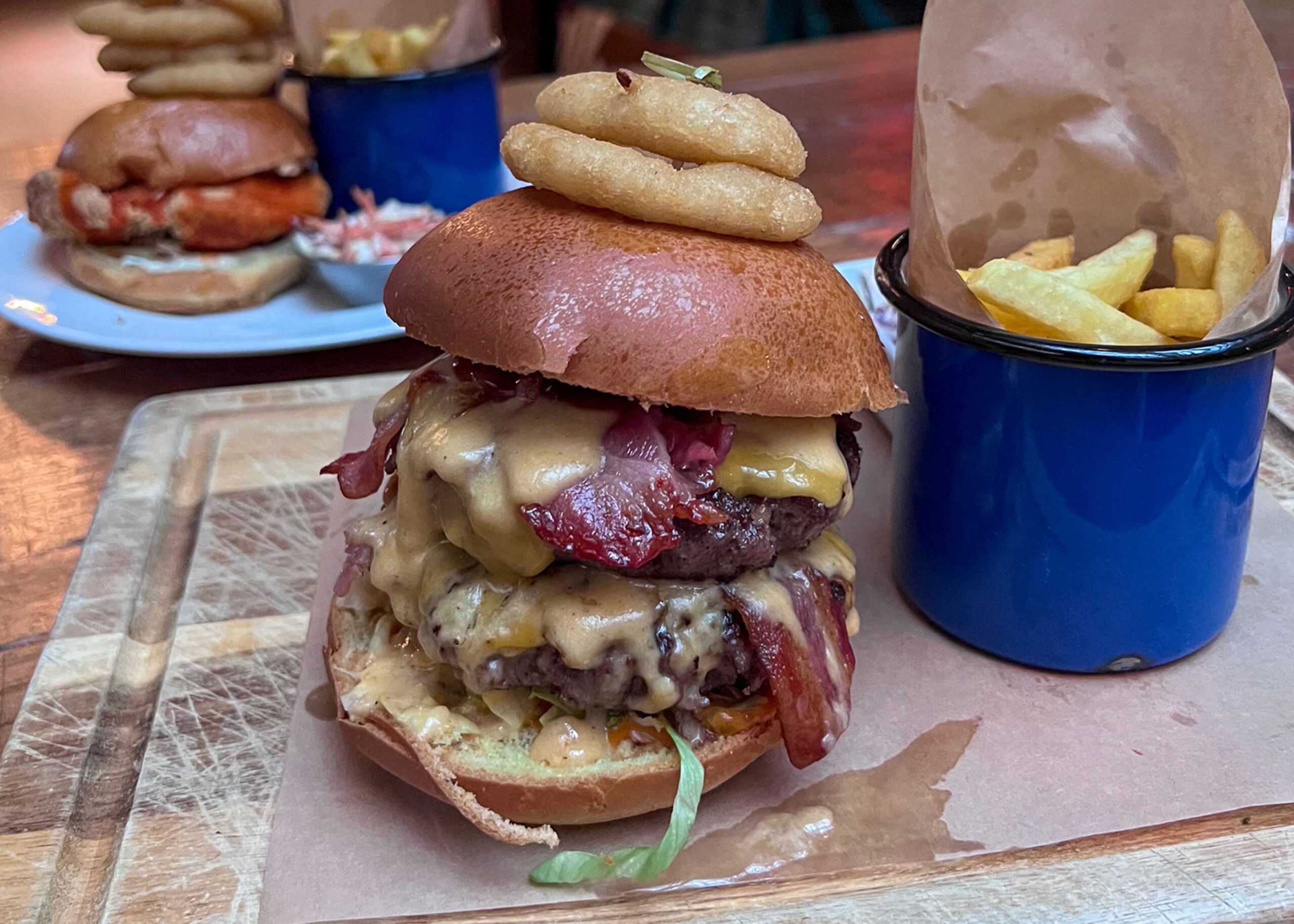 Double stacked beef burger with onion rings on top from Revolution